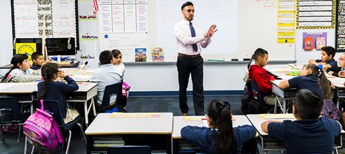 NBCT Anthony Perez speaks to students from the front of his classroom as students are seated in their desks.